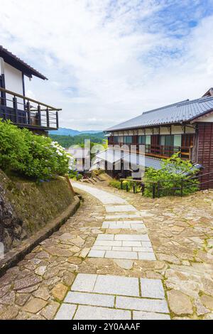 Der restaurierte, geschwungene Steinweg führt zu traditionellen Holzhäusern auf dem alten Nakasendo-Weg an einem wunderschönen Tag in Magome, Kiso Valley, Japa Stockfoto