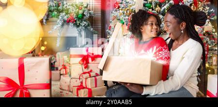 Gerne afrikanische Mutter und Tochter Eröffnung zauberhafte Weihnachten Geschenkverpackung Stockfoto