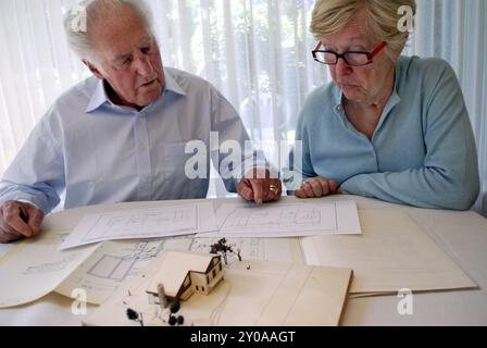 Ein älteres Paar, das sich einen Grundriss und ein Hausmodell ansieht Stockfoto