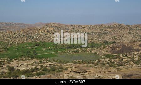 Grüne Oase der Reisfelder zwischen Granitbergen. Einzigartige Landschaft in Hampi, Indien, Asien Stockfoto