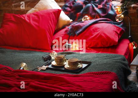 Weihnachtsdekoration und Teetassen auf dem Bett. Nahaufnahme Stockfoto