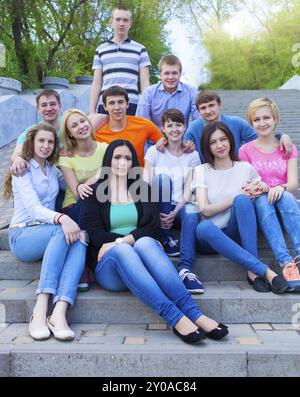 Gruppe von lächelnden Jugendlichen im Freien sitzen. Freundschaft-Konzept Stockfoto