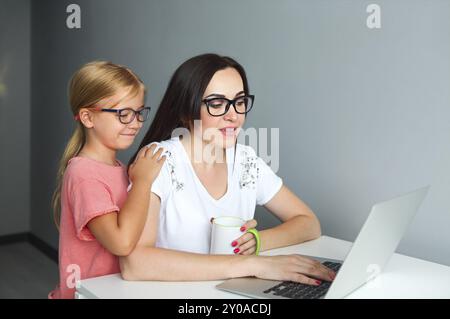 Beschäftigte Mutter von zu Hause aus arbeiten mit kleinen Tochter Stockfoto