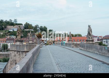 Fußgänger und Steinstatuen auf der Alten Mainbrücke - Alte Mainbrücke - in der historischen deutschen Stadt Würzburg an einem bewölkten Sommertag. Stockfoto