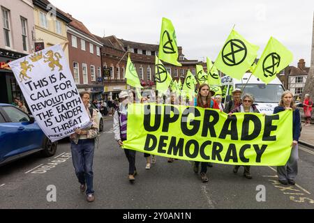 Windsor, Großbritannien. 31. August 2024. Klimaaktivisten der Extinction Rebellion marschieren mit Spruchbändern nach Windsor Castle, um Briefe an König Karl III. Am zweiten von drei Tagen der Aufrüstung der Demokratie zu liefern. Die Kampagne „Upgrade Democracy“ von Extinction Rebellion soll die Art und Weise hervorheben, wie die Gewinne der Öl- und Gasunternehmen im Vereinigten Königreich gesichert werden, und die britische Regierung auffordern, eine Bürgerversammlung für Klima- und ökologische Gerechtigkeit zu gründen und von ihr geleitet zu werden. Quelle: Mark Kerrison/Alamy Live News Stockfoto