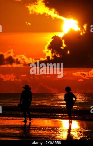 Isle Of Palms, Usa. 31. August 2024. Ein Paar, das von der Sonnenaufgangswache umrahmt wird, während die Sonne unter einer Sturmwolke am Anfang des Labor Day-Wochenendes am Strand am 31. August 2024 in Isle of Palms, South Carolina, ausbricht. Quelle: Richard Ellis/Richard Ellis/Alamy Live News Stockfoto