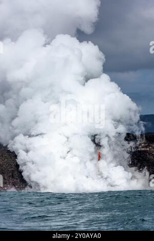 Der Ausbruch des Kilauea-Vulkans auf Hawaii bildete eine Lavaröhre, die an der Seite einer Klippe herauskam und in den Ozean mündete, was Explosionen und Dampf verursachte. Stockfoto