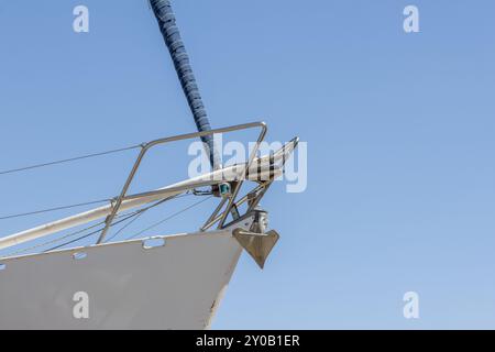 Der Segelbootbogen zeigt einen gerollten Jib und Anker mit blauem Himmel im Hintergrund Stockfoto