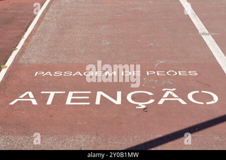 Weißes Fußgängerschild auf einem roten Radweg mit dem Wort Achtung auf portugiesisch Stockfoto