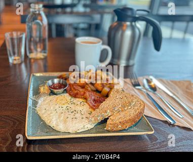 Traditionelles Frühstück mit Spiegeleiern, Speck, Kartoffeln, Toast und Kaffee Stockfoto