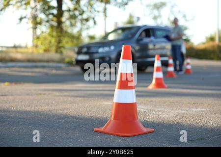 Der Prüfer, der den Schüler vor der Prüfung auf der Fahrschule anweist, konzentriert sich auf den Verkehrskegel Stockfoto