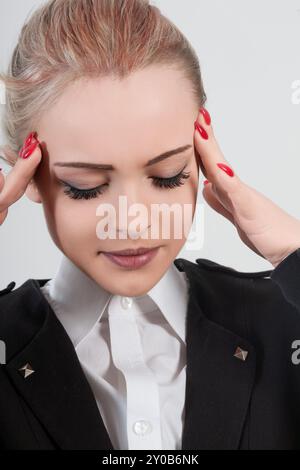 Gestresste Geschäftsfrau mit geschlossenen Augen, die Schläfen mit Schmerzen berührt. Von der Arbeit überwältigt, müde und unglücklich in einem Firmenbüro Stockfoto
