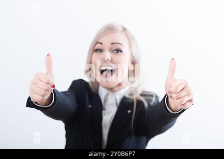 Die freudige Geschäftsfrau zeigt sich mit zwei Daumen hoch und strahlt positive Einstellung und Erfolg in professioneller Kleidung vor weißem Hintergrund aus Stockfoto