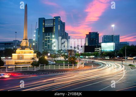 Nach Sonnenuntergang, während der Hauptverkehrszeit, rasen die unscharfen Bewegungen der Fahrzeuge um den geschäftigen Kreisverkehr im Stadtzentrum. Stockfoto