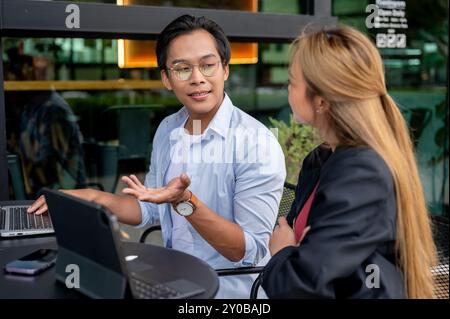 Ein kluger, gutaussehender asiatischer Geschäftsmann trifft sich in einem Café mit seinem Kollegen, teilt seine Ideen und arbeitet ein Brainstorming aus. Stockfoto