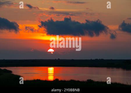 Sonnenaufgang über Lagune am östlichen Ende von Galveston mit Reflexion des Sonnenwegs im Wasser. Stockfoto