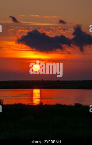 Sonnenaufgang über Lagune am östlichen Ende von Galveston mit Reflexion des Sonnenwegs im Wasser. Stockfoto