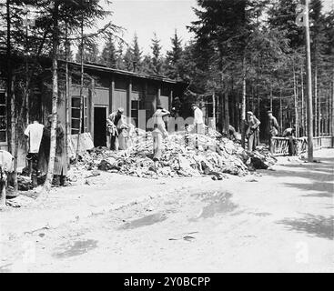 Überlebende suchen in Ebensee nach Kleiderstapeln. Ebensee war ein Außenlager des Konzentrationslagers Mauthausen, das 1943 von der SS errichtet wurde, um Tunnel für die Rüstungslagerung in der Nähe der Stadt Ebensee zu bauen. Obwohl der Mauthausen-Komplex kein Vernichtungszentrum war, waren Grausamkeit und Vernachlässigung alltäglich. Zwischen 8.500 und 11.000 Gefangene starben im Lager, meist an Hunger oder Unterernährung. Die US-Armee befreite das Lager am 6. Mai 1945. Stockfoto