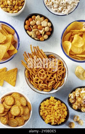 Salzige Snacks, Partymix, eine Auswahl knuspriger Vorspeisen, von oben geschossen. Tortilla und Kartoffelchips, Cracker, Popcorn usw., Lebensmittelfotografie Stockfoto