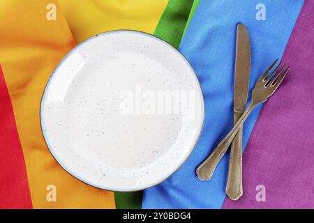 Gay Food Konzept. Ein Teller mit Besteck, ein flacher Lay-Shot über der LGBTQ-Regenbogenflagge, Lebensmittelfotografie Stockfoto