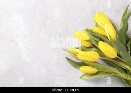 Blumenstrauß aus gelben Tulpen auf grauem Steingrund Draufsicht, flacher Laienkopierraum Stockfoto