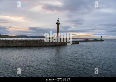 Abendlicht über dem West Pier im Hafen von Whitby, North Yorkshire, England, Großbritannien, vom East Pier aus gesehen Stockfoto