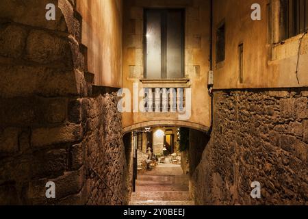 Stadt Girona bei Nacht in Katalonien, Spanien. Altes jüdisches Viertel, der Ruf, mittelalterliche Steinmauern, Zimmer mit Fenster auf einer winzigen Brücke zwischen zwei Gebäuden Stockfoto