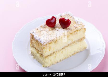 Französische Mille feuille Kuchen mit Vanillecreme mit Herzen auf einem rosa Hintergrund für den Valentinstag eingerichtet Stockfoto