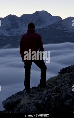 Wanderer mit Blick über das nebelbedeckte Atndalen-Tal zum Gipfel des Rondslottet im Rondane-Nationalpark, Hedmark Fylke, Norwegen, Oktober 2011, Euro Stockfoto