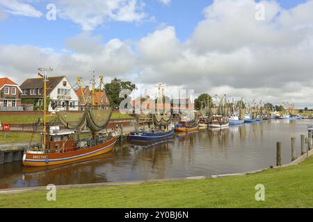 Blick auf historische Häuser mit bunten Fassaden am alten Hafen von Greetsiel, mit Fischerboot, unter blauem Himmel, Greetsiel, Ostfriesland, Niedersachsen Stockfoto