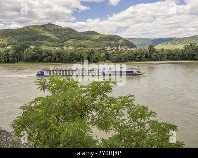 Ein Kreuzfahrtschiff segelt entlang des Flusses, umgeben von Hügeln und Bäumen, Duernstein, Wachau, Donau, Österreich, Europa Stockfoto