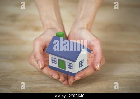 Das kleine Haus an den Händen und die Frau. Symbol eines erfolgreichen Immobiliengeschäfts Stockfoto