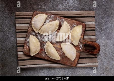 Traditionelles polnisches Gericht, Teigtaschen, roh, gefroren, auf einem Schneidebrett, Holztisch, Blick von oben, keine Leute Stockfoto