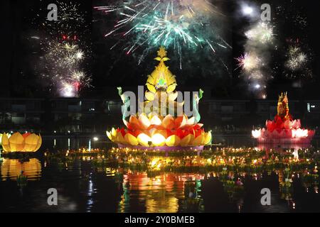 Große und kleine Boote mit Kerzen und Blumen sind für Thailands traditionelle Loy Krathong Festival gegeben. Feuerwerk am Himmel Stockfoto