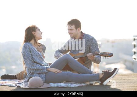 Junger Mann und Frau mit Gitarre, die Spaß im Freien haben Liebe und Beziehungen Konzept Stockfoto