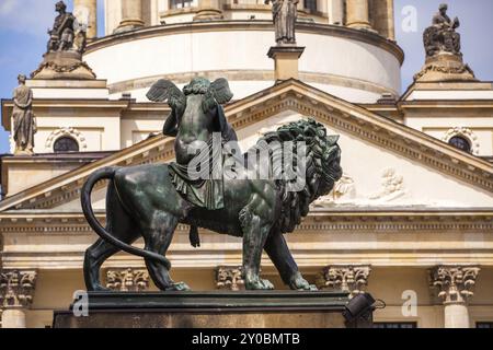 Statue eines Engels, der auf einem Löwen reitet und Harfe spielt, mit der französischen Kathedrale im Hintergrund Stockfoto