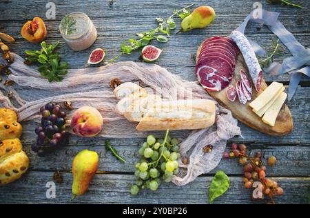 Picknick am Strand bei Sonnenuntergang im Boho-Stil. Romantisches Abendessen, Party mit Freunden, Sommerzeit, Speisen- und Getränkekonzept Stockfoto