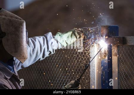 Schwere Industrie Schweißgerät Arbeiter in Schutzmaske Hand arc Schweißbrenner arbeiten auf Metall Bau Stockfoto