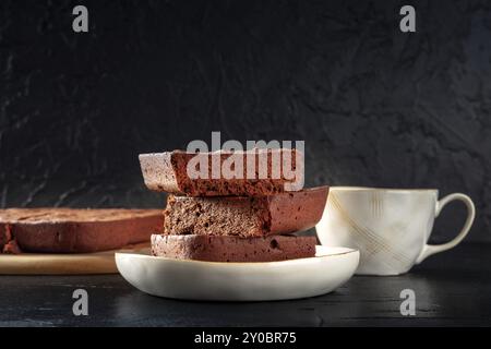 Schokoladenbrownie mit Tee, einfacher Kaffeekuchen, Seitenansicht auf schwarzem Hintergrund mit Kopierraum, Lebensmittelfotografie Stockfoto