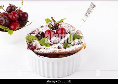 Französische Clafoutis mit Kirsche in Keramik Förmchen auf weißer Holztisch Stockfoto