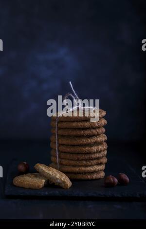 Gesunde hausgemachte Haferflockenkekse mit Haselnüssen auf dunklem rustikalem Hintergrund, dezent Stockfoto