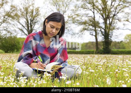 Kolumbianische Frau schriftlich Wiese mit Frühlingsblumen Stockfoto