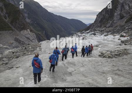 Franz Josef, Neuseeland, 22. März 2015: Eine Gruppe von Touristen, die auf dem Franz-Josef-Gletscher in Ozeanien in Richtung eines Hubschraubers wandern Stockfoto