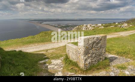 Ein Steinsitz auf dem South West Coast Path mit Blick in Richtung Fortuneswell und Chesil Beach, Isle of Portland, Jurassic Coast, Dorset, Großbritannien, mit Wolken o Stockfoto