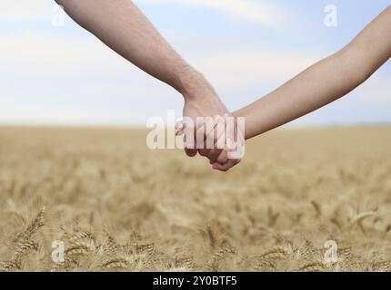 Junges Paar Hand in Hand im Feld. Close-up Stockfoto