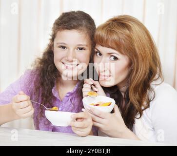 Glückliche Mutter und Tochter essen Müsli und Obst Stockfoto