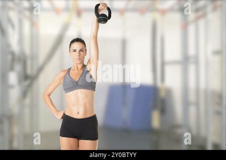 Fit Woman Workout mit einer Kettlebell, isoliert in grau Stockfoto