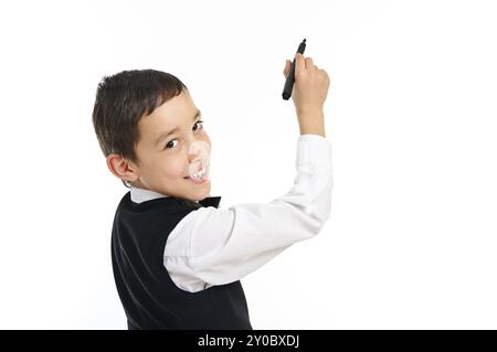 Porträt eines jungen Schuljungen, der sich windet oder etwas mit schwarzem Stift zeichnet, isoliert auf weißem Hintergrund Stockfoto