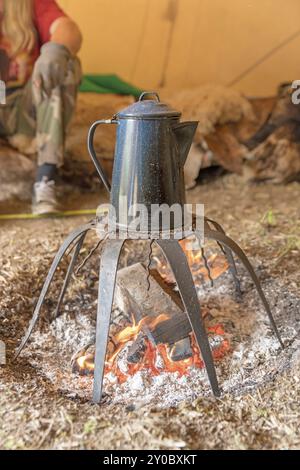 Alte Kaffeekanne steht über einem Lagerfeuer auf einem Stand Stockfoto