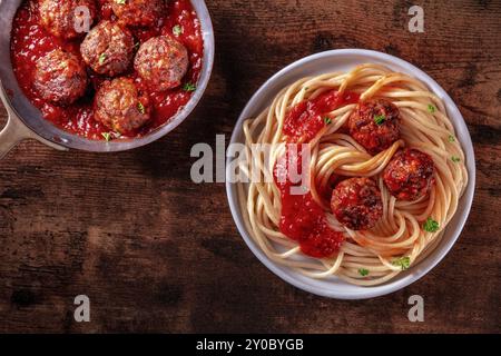 Fleischbällchen. Rindfleischbällchen, oben in einer Pfanne und mit einem Teller Spaghetti-Pasta, auf einem rustikalen hölzernen Hintergrund, mit Tomatensauce, Lebensmittelfotografie, Stockfoto